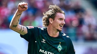 Werder-Stürmer Nick Woltemade reckt jubelnd seinen Arm empor nach einem Treffer.