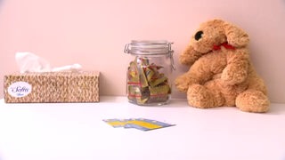Auf einem Tiosch sind neben einem Stoff-Teddy auch Gummibärchen und Taschentücher platziert