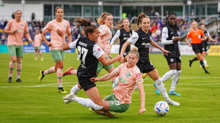Mehrere Spielerinnen von Werder Bremen und Eintracht Frankfurt kämpfen um den Ball.