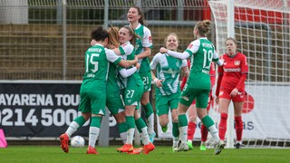 Werders Fußballerinnen bejubeln in einer Traube auf dem Spielfeld ihren Treffer gegen die Leverkusenerinnen.