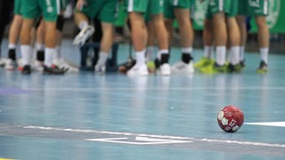 Mehrere Handball-Spieler bilden in einer Halle einen Teamkreis.