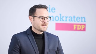 FDP-Landesvorsitzender Thore Schäck vor einem FDP-Schriftzug
