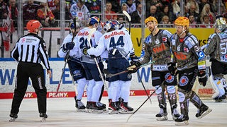Enttäuschte Eishockey-Spieler der Fischtown Pinguins auf dem Eis, während neben ihnen Münchner Spieler einen Treffer bejubeln.