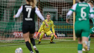 Werders Torhüterin Anneke Borbe fokussiert sich auf den Angriff einer Frankfurter Spielerin, die auf sie zuläuft.