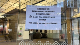 Ein Schild mit der Info, dass Karstadt heute wegen einer Betriebsversammlung später öffnet, hängt am Eingang der Filiale.