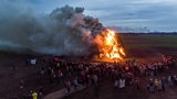 Aus der Ferne ist zu sehen, wie ein Osterfeuer unter großer Rauchentwicklung abbrennt. 