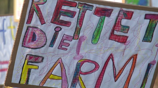 Ein Banner auf dem mit Bundstiften "rettet die Farm" gemalt wurde.