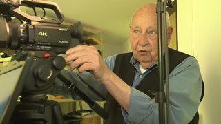 Ein Rentner stellt in einem Keller eine TV-Kamera ein. Dort produziert er eine eigene Fernsehsendung.