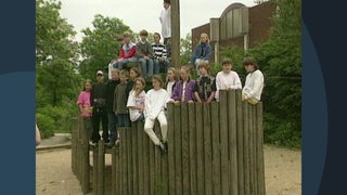 Viele Kinder auf einem Klettergerüst aus Holz.