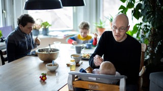 Eine Familie mit 2 Kindern sitzt gemeinsam beim Essen am Tisch.