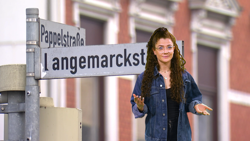 Patricia Friedek steht vor einem Schild mit der Aufschrift "Langemarckstraße"