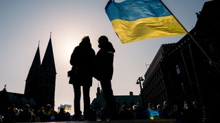 Die ukrainische Nationalfahne weht während einer Kundgebung gegen den Krieg in der Ukraine auf dem Domshof im Wind.