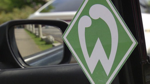 Zu sehen ist ein werder Logo, welches in einem Auto hängt.