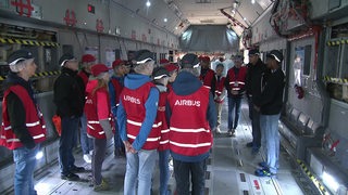 Mehrere Schüler stehen im militärischen Flugzeug beim Airbus. 